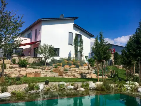 Naturnaher Garten mit Schwimmteich, Findlingen und modernem Wohnhaus