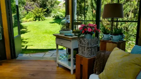 Blick aus einem Wintergarten über die Terrasse in den Garten