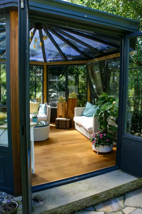 Gläserner Gartenpavillon mit Sitzplatz, umgeben von Ziergräsern