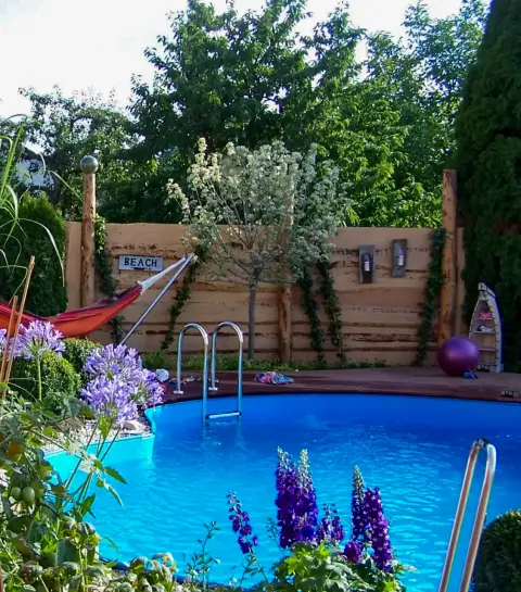 Pool mit Schmucklilien, Hängematte und Holzwand