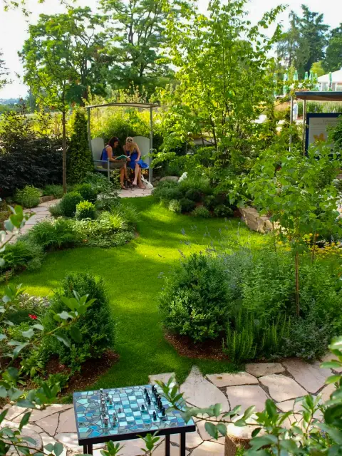 Ruhiger Sitzplatz mit Gartenbank und Schachtisch in einem gepflegten Garten