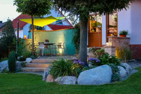 Abendliche Terrasse mit Sonnensegel, Findlingen und Hortensien