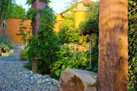 Kiesgarten mit Findlingen, Holzstelen und Terracotta-Wand