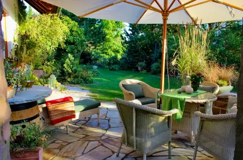 Terrasse mit Sonnenschirm und Sitzgruppe, umgeben von Gräsern