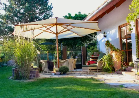 Gemütlicher Terrassensessel mit bepflanztem Kübel im Abendlicht
