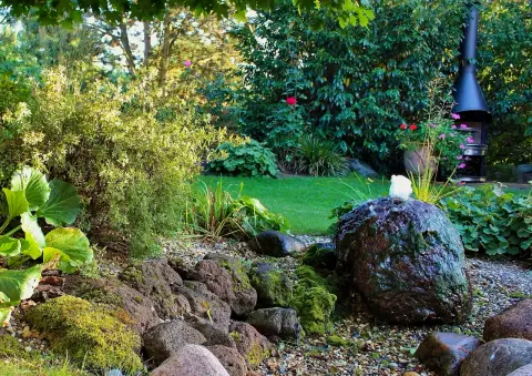 Gartenvista mit Rasenweg zu einem Pavillon zwischen Staudenbeeten