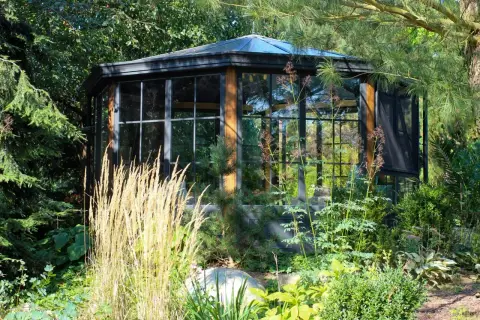 Gläserner Pavillon mit Ziergräsern im Garten