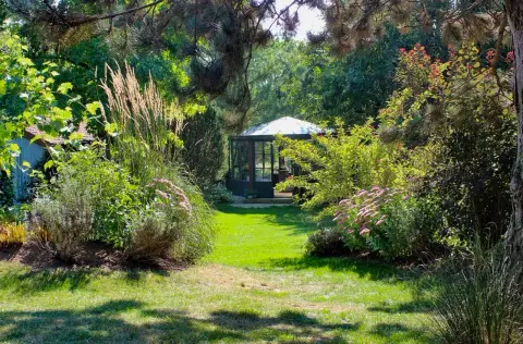 Weiter Blick über einen Garten mit Rasenweg zu einem Pavillon