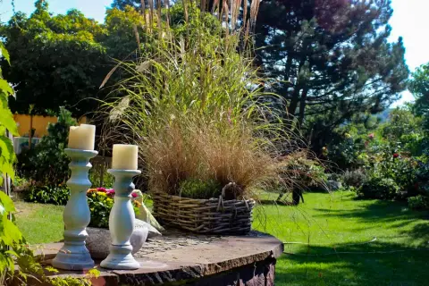 Kerzen auf Ständern, dahinter der abendliche Garten