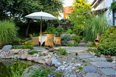 Terrasse mit Sonnenschirm und Sitzplatz an einem Kiesbeet