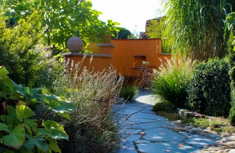Gartenweg mit Ziergräsern und einer Steinkugel als Blickfang