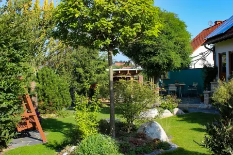Gartenüberblick mit Wohnhaus, Findlingen und Rasen