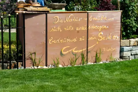 Cortenstahl-Wand mit eingraviertem Naturspruch im Garten