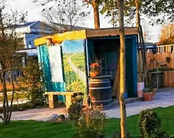 Blick in den Qi-Gardens-Schaugarten auf der Landesgartenschau Höxter 2023: Pergola mit Landschaftsmotiv, Weinfässern und Natursteinflächen