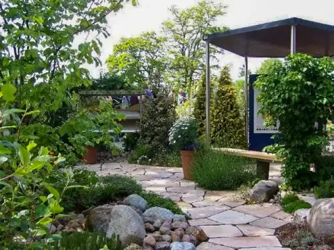 Fertig gestalteter Schaugarten mit Pavillon, Natursteinweg und Bepflanzung