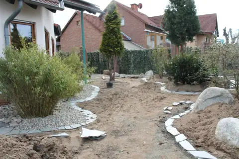 Bauphase: neu angelegte Beete mit Sand und Steinkanten, erste Gehölze