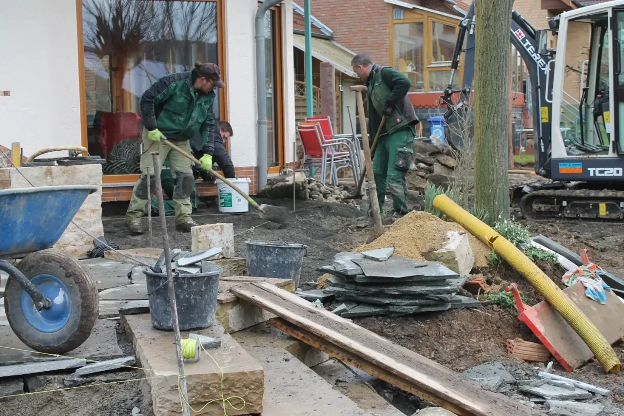 Bauphase: Verlegen von Natursteinplatten an der Terrasse – das Team bei der Arbeit