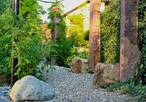 Fertiger Garten: Kiesweg zwischen Sandstein-Stelen und begrünter Wand