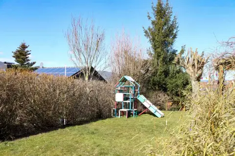 Ausgangssituation: weite Rasenfläche mit Spielturm und hoher Hecke