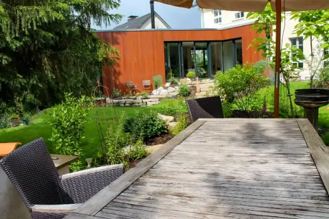 Fertiger Garten: Holzsteg und Bepflanzung vor modernem Wohnhaus