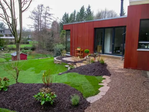 Fertiger Garten: geschwungenes Beet und Rasen am Haus