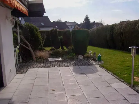 Ausgangslage: gepflasterte Terrasse mit schmalem Rasenstreifen und wenig Bepflanzung