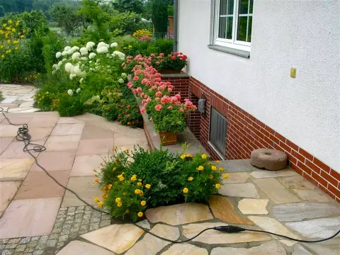 Ergebnis: bepflanzte Terrasse mit Natursteinbelag, Staudenbeeten und blühenden Kübeln