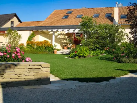Ergebnis: fertiger Garten mit Pergola, Rasenfläche, Natursteinmauer und gewachsener Bepflanzung