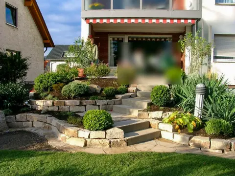 Ergebnis: terrassierter Vorgarten mit Natursteinmauern, Stauden und überdachtem Sitzplatz