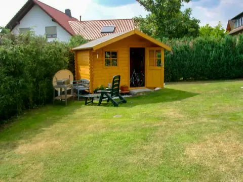 Ausgangslage: gelbes Gartenhaus an einer einfachen Rasenfläche