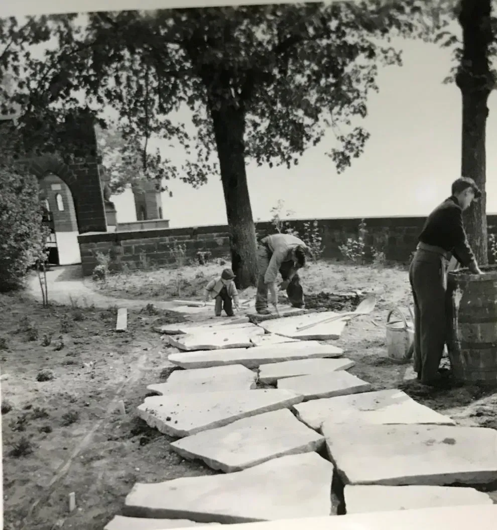 Historische Schwarz-Weiß-Familienaufnahme: Gartenbau an der Burg Hohenzollern, Verlegen von Polygonalplatten, ein Kind hilft mit