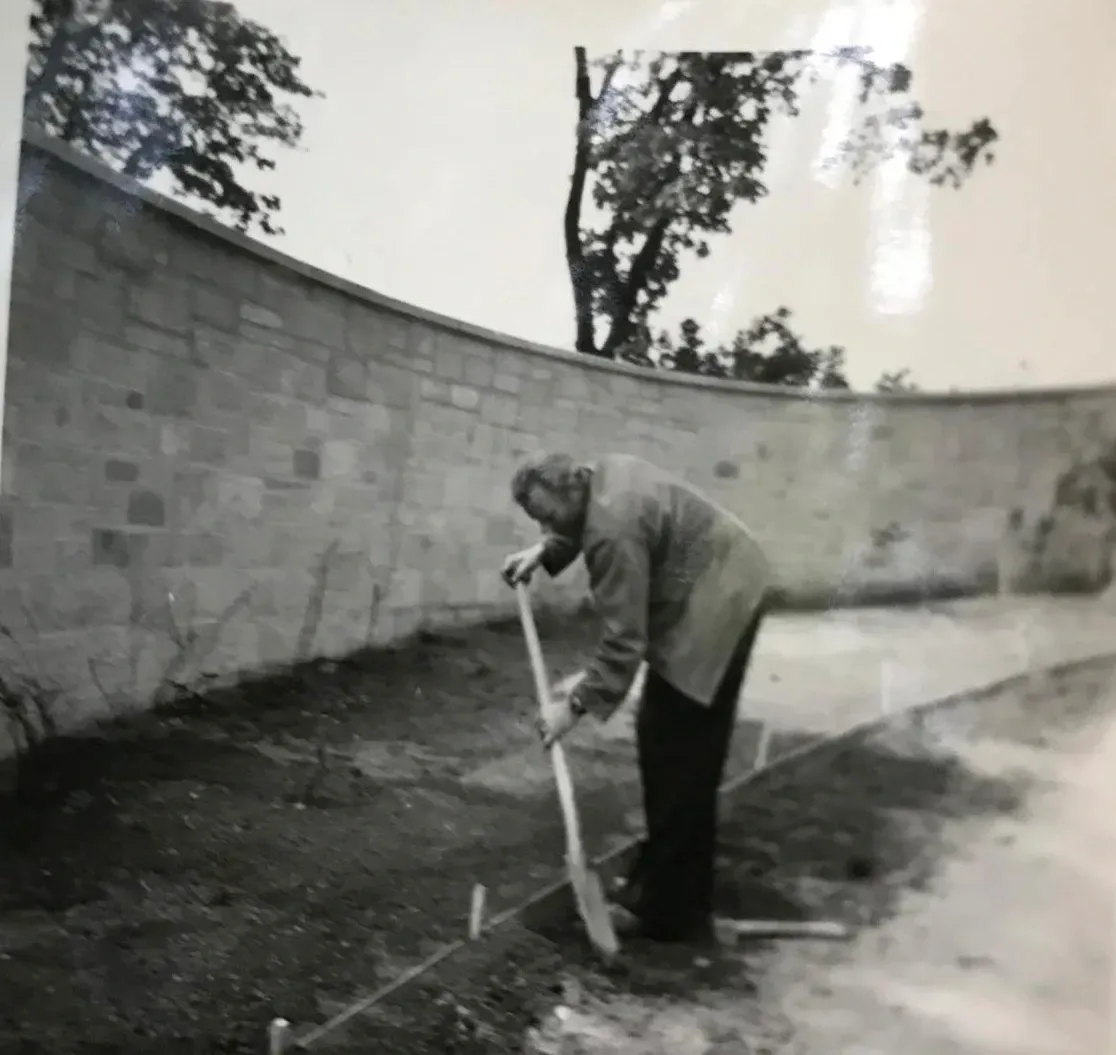 Historische Schwarz-Weiß-Familienaufnahme: der Vater der Inhaberin bei Gartenarbeiten an einer geschwungenen Sandsteinmauer, Burg Hohenzollern